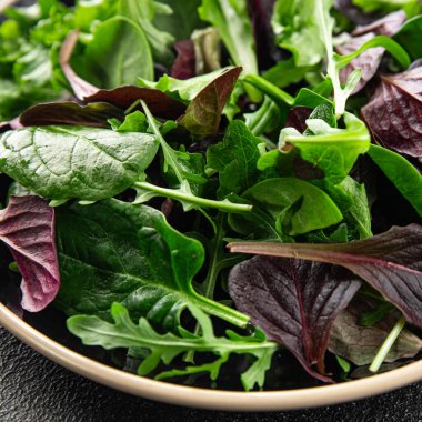 Sağlıklı salata yaprakları karışık salata sulu çerez sebzeler, roka, marul, meşe yaprağı, yeşil yaprak salatası taze yemek arkaplanı masadaki kırsal yiyecekler üst görünüm vejetaryen ve vejetaryen