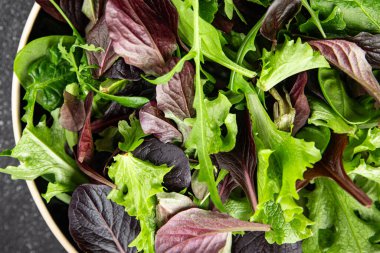Sağlıklı salata yaprakları karışık salata sulu çerez sebzeler, roka, marul, meşe yaprağı, yeşil yaprak salatası taze yemek arkaplanı masadaki kırsal yiyecekler üst görünüm vejetaryen ve vejetaryen