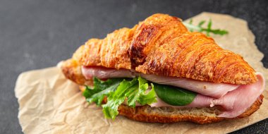 Kruvasan sandviçi, jambon, peynir, yeşil yaprak salatası lezzetli gurme yemek arkaplanı masa kırsal yiyeceklerin üst görünümü fotokopi alanı