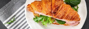 Kruvasan sandviçi, jambon, peynir, yeşil yaprak salatası lezzetli gurme yemek arkaplanı masa kırsal yiyeceklerin üst görünümü fotokopi alanı