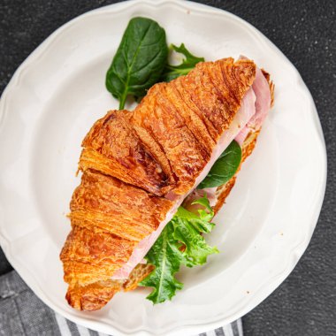 Kruvasan sandviçi, jambon, peynir, yeşil yaprak salatası lezzetli gurme yemek arkaplanı masa kırsal yiyeceklerin üst görünümü fotokopi alanı
