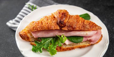 Kruvasan sandviçi, jambon, peynir, yeşil yaprak salatası lezzetli gurme yemek arkaplanı masa kırsal yiyeceklerin üst görünümü fotokopi alanı