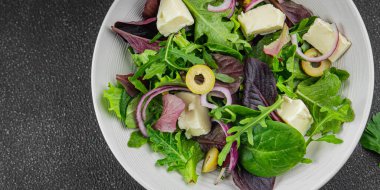 Salata zeytinleri, peynir ve yeşil yapraklar taze gurme yemek arkaplanı masa üzerinde rustik gıda üst görünüm fotokopi uzay vejetaryen gıda