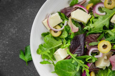 Salata zeytinleri, peynir ve yeşil yapraklar taze gurme yemek arkaplanı masa üzerinde rustik gıda üst görünüm fotokopi uzay vejetaryen gıda