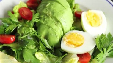 Salata avokado, haşlanmış yumurta, domates, yeşil yaprak marul, sebze tabağı taze lezzetli gurme yemek arkaplanı masa kırsal yiyeceklerin üst görünümü fotokopi alanı.