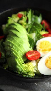 Salata avokado, haşlanmış yumurta, domates, yeşil yaprak marul, sebze tabağı taze lezzetli gurme yemek arkaplanı masa kırsal yiyeceklerin üst görünümü fotokopi alanı.