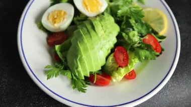 Salata avokado, haşlanmış yumurta, domates, yeşil yaprak marul, sebze tabağı taze lezzetli gurme yemek arkaplanı masa kırsal yiyeceklerin üst görünümü fotokopi alanı.