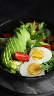 Salata avokado, haşlanmış yumurta, domates, yeşil yaprak marul, sebze tabağı taze lezzetli gurme yemek arkaplanı masa kırsal yiyeceklerin üst görünümü fotokopi alanı.