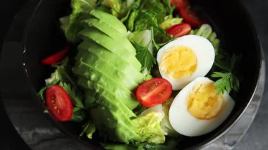 Salata avokado, haşlanmış yumurta, domates, yeşil yaprak marul, sebze tabağı taze lezzetli gurme yemek arkaplanı masa kırsal yiyeceklerin üst görünümü fotokopi alanı.