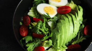 Salata avokado, haşlanmış yumurta, domates, yeşil yaprak marul, sebze tabağı taze lezzetli gurme yemek arkaplanı masa kırsal yiyeceklerin üst görünümü fotokopi alanı.