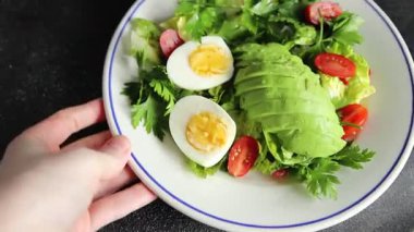 Salata avokado, haşlanmış yumurta, domates, yeşil yaprak marul, sebze tabağı taze lezzetli gurme yemek arkaplanı masa kırsal yiyeceklerin üst görünümü fotokopi alanı.