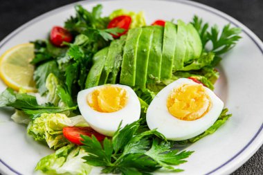 Avokado salatası, haşlanmış yumurta, domates, yeşil yaprak marulu, sebze tabağı taze lezzetli gurme yemek arkaplanı masa kırsal yiyeceklerin üst görünümü fotokopi alanı. 