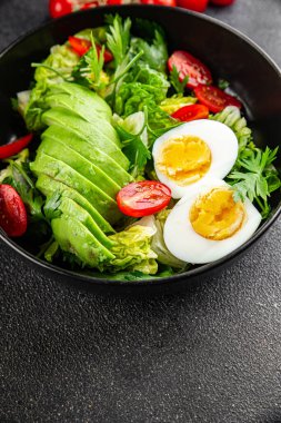 Avokado salatası, haşlanmış yumurta, domates, yeşil yaprak marulu, sebze tabağı taze lezzetli gurme yemek arkaplanı masa kırsal yiyeceklerin üst görünümü fotokopi alanı. 