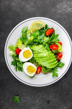 Avokado salatası, haşlanmış yumurta, domates, yeşil yaprak marulu, sebze tabağı taze lezzetli gurme yemek arkaplanı masa kırsal yiyeceklerin üst görünümü fotokopi alanı. 