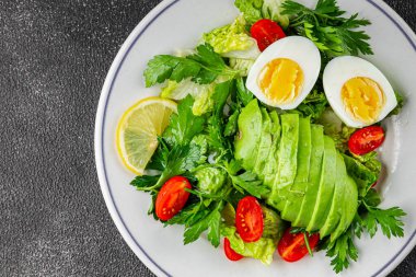 Avokado salatası, haşlanmış yumurta, domates, yeşil yaprak, marul, sebze yemeği taze lezzetli gurme yemek arka planda masanın üstünde rustik yiyecekler fotokopi alanı keto ve paleo diyeti vejetaryen yemekleri