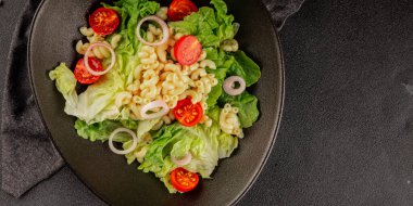 Makarna salatası yeşil yaprak marul, domates, makarna, soğan taze lezzetli gurme yemek arkaplan masa üzerinde rustik gıda üst görünüm fotokopi alanı keto ve paleo diyet vegan ve vejetaryen gıda