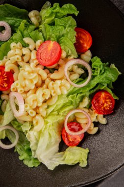 Makarna salatası yeşil yaprak marul, domates, makarna, soğan taze lezzetli gurme yemek arkaplan masa üzerinde rustik gıda üst görünüm fotokopi alanı keto ve paleo diyet vegan ve vejetaryen gıda