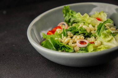 Makarna salatası yeşil yaprak marul, domates, makarna, soğan taze lezzetli gurme yemek arkaplan masa üzerinde rustik gıda üst görünüm fotokopi alanı keto ve paleo diyet vegan ve vejetaryen gıda