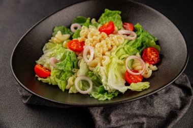 Makarna salatası yeşil yaprak marul, domates, makarna, soğan taze lezzetli gurme yemek arkaplan masa üzerinde rustik gıda üst görünüm fotokopi alanı keto ve paleo diyet vegan ve vejetaryen gıda