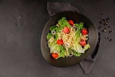 Makarna salatası yeşil yaprak marul, domates, makarna, soğan taze lezzetli gurme yemek arkaplan masa üzerinde rustik gıda üst görünüm fotokopi alanı keto ve paleo diyet vegan ve vejetaryen gıda