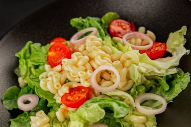 Makarna salatası yeşil yaprak marul, domates, makarna, soğan taze lezzetli gurme yemek arkaplan masa üzerinde rustik gıda üst görünüm fotokopi alanı keto ve paleo diyet vegan ve vejetaryen gıda