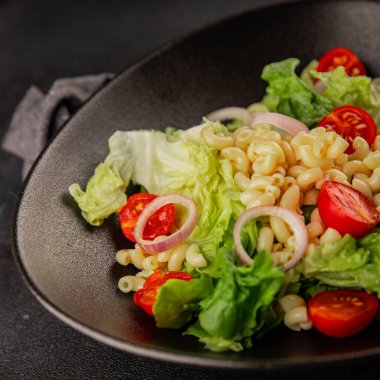 Makarna salatası yeşil yaprak marul, domates, makarna, soğan taze lezzetli gurme yemek arkaplan masa üzerinde rustik gıda üst görünüm fotokopi alanı keto ve paleo diyet vegan ve vejetaryen gıda