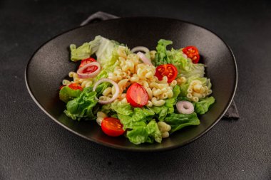 Makarna salatası yeşil yaprak marul, domates, makarna, soğan taze lezzetli gurme yemek arkaplan masa üzerinde rustik gıda üst görünüm fotokopi alanı keto ve paleo diyet vegan ve vejetaryen gıda