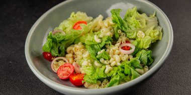 Makarna salatası yeşil yaprak marul, domates, makarna, soğan taze lezzetli gurme yemek arkaplan masa üzerinde rustik gıda üst görünüm fotokopi alanı keto ve paleo diyet vegan ve vejetaryen gıda
