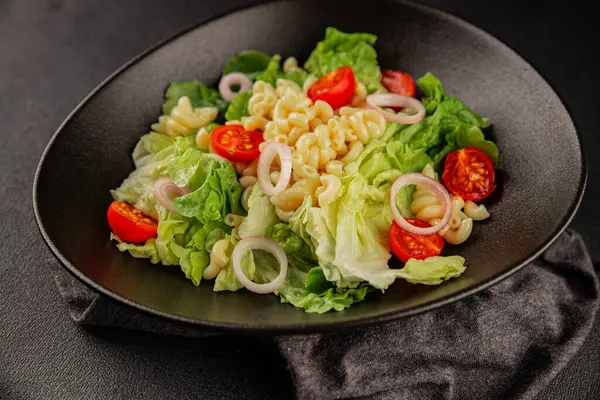 Makarna salatası yeşil yaprak marul, domates, makarna, soğan taze lezzetli gurme yemek arkaplan masa üzerinde rustik gıda üst görünüm fotokopi alanı keto ve paleo diyet vegan ve vejetaryen gıda