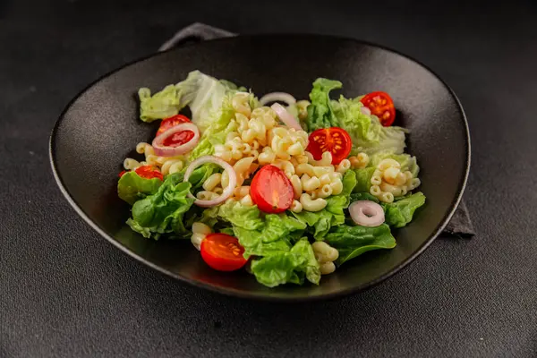 Makarna salatası yeşil yaprak marul, domates, makarna, soğan taze lezzetli gurme yemek arkaplan masa üzerinde rustik gıda üst görünüm fotokopi alanı keto ve paleo diyet vegan ve vejetaryen gıda