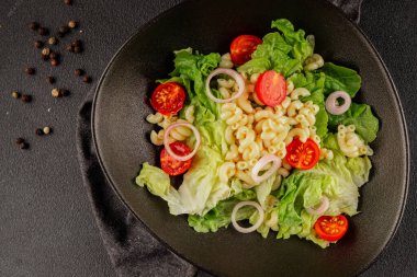 Makarna salatası yeşil yaprak marul, domates, makarna, soğan taze lezzetli gurme yemek arkaplan masa üzerinde rustik gıda üst görünüm fotokopi alanı keto ve paleo diyet vegan ve vejetaryen gıda