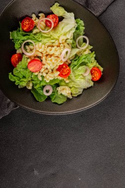Makarna salatası yeşil yaprak marul, domates, makarna, soğan taze lezzetli gurme yemek arkaplan masa üzerinde rustik gıda üst görünüm fotokopi alanı keto ve paleo diyet vegan ve vejetaryen gıda