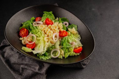 Makarna salatası yeşil yaprak marul, domates, makarna, soğan taze lezzetli gurme yemek arkaplan masa üzerinde rustik gıda üst görünüm fotokopi alanı keto ve paleo diyet vegan ve vejetaryen gıda