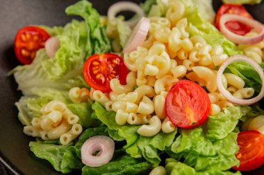 Makarna salatası yeşil yaprak marul, domates, makarna, soğan taze lezzetli gurme yemek arkaplan masa üzerinde rustik gıda üst görünüm fotokopi alanı keto ve paleo diyet vegan ve vejetaryen gıda