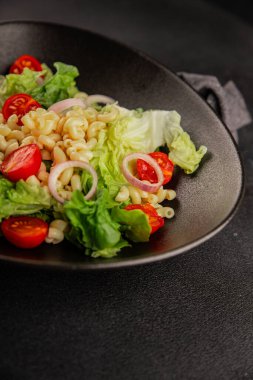 Makarna salatası yeşil yaprak marul, domates, makarna, soğan taze lezzetli gurme yemek arkaplan masa üzerinde rustik gıda üst görünüm fotokopi alanı keto ve paleo diyet vegan ve vejetaryen gıda