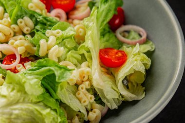 Makarna salatası yeşil yaprak marul, domates, makarna, soğan taze lezzetli gurme yemek arkaplan masa üzerinde rustik gıda üst görünüm fotokopi alanı keto ve paleo diyet vegan ve vejetaryen gıda