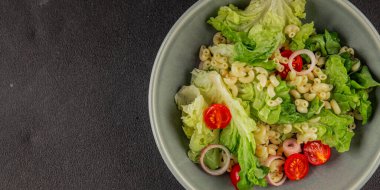 Makarna salatası yeşil yaprak marul, domates, makarna, soğan taze lezzetli gurme yemek arkaplan masa üzerinde rustik gıda üst görünüm fotokopi alanı keto ve paleo diyet vegan ve vejetaryen gıda