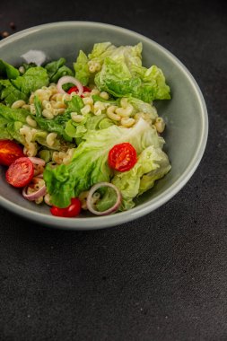 Makarna salatası yeşil yaprak marul, domates, makarna, soğan taze lezzetli gurme yemek arkaplan masa üzerinde rustik gıda üst görünüm fotokopi alanı keto ve paleo diyet vegan ve vejetaryen gıda
