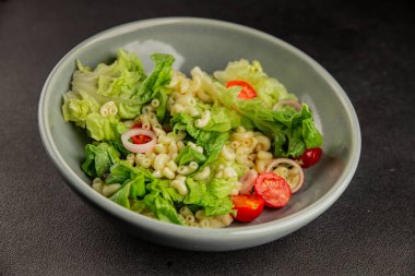 Makarna salatası yeşil yaprak marul, domates, makarna, soğan taze lezzetli gurme yemek arkaplan masa üzerinde rustik gıda üst görünüm fotokopi alanı keto ve paleo diyet vegan ve vejetaryen gıda