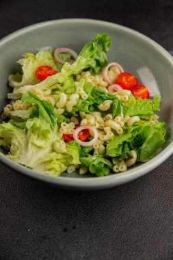 Makarna salatası yeşil yaprak marul, domates, makarna, soğan taze lezzetli gurme yemek arkaplan masa üzerinde rustik gıda üst görünüm fotokopi alanı keto ve paleo diyet vegan ve vejetaryen gıda
