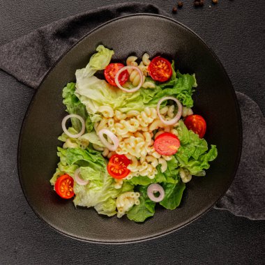 Makarna salatası yeşil yaprak marul, domates, makarna, soğan taze lezzetli gurme yemek arkaplan masa üzerinde rustik gıda üst görünüm fotokopi alanı keto ve paleo diyet vegan ve vejetaryen gıda