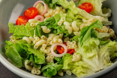 Makarna salatası yeşil yaprak marul, domates, makarna, soğan taze lezzetli gurme yemek arkaplan masa üzerinde rustik gıda üst görünüm fotokopi alanı keto ve paleo diyet vegan ve vejetaryen gıda