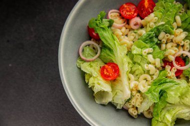 Makarna salatası yeşil yaprak marul, domates, makarna, soğan taze lezzetli gurme yemek arkaplan masa üzerinde rustik gıda üst görünüm fotokopi alanı keto ve paleo diyet vegan ve vejetaryen gıda