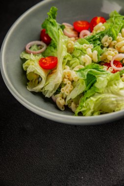 Makarna salatası yeşil yaprak marul, domates, makarna, soğan taze lezzetli gurme yemek arkaplan masa üzerinde rustik gıda üst görünüm fotokopi alanı keto ve paleo diyet vegan ve vejetaryen gıda