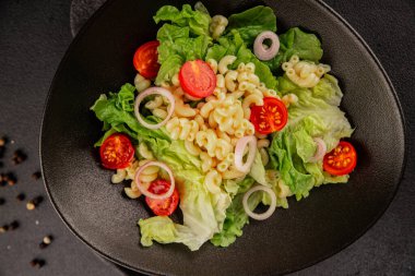 Makarna salatası yeşil yaprak marul, domates, makarna, soğan taze lezzetli gurme yemek arkaplan masa üzerinde rustik gıda üst görünüm fotokopi alanı keto ve paleo diyet vegan ve vejetaryen gıda