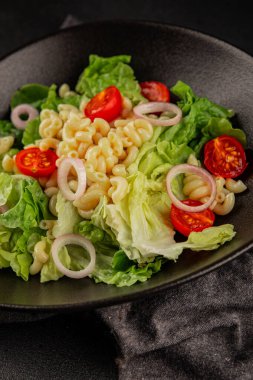 Makarna salatası yeşil yaprak marul, domates, makarna, soğan taze lezzetli gurme yemek arkaplan masa üzerinde rustik gıda üst görünüm fotokopi alanı keto ve paleo diyet vegan ve vejetaryen gıda