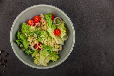 Makarna salatası yeşil yaprak marul, domates, makarna, soğan taze lezzetli gurme yemek arkaplan masa üzerinde rustik gıda üst görünüm fotokopi alanı keto ve paleo diyet vegan ve vejetaryen gıda