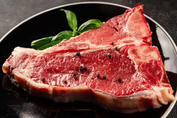 Çiğ biftek T-bone taze et prim biftek aperatif taze lezzetli gurme yemek arka planı masa rustik gıda üst görünüm fotokopi alanı