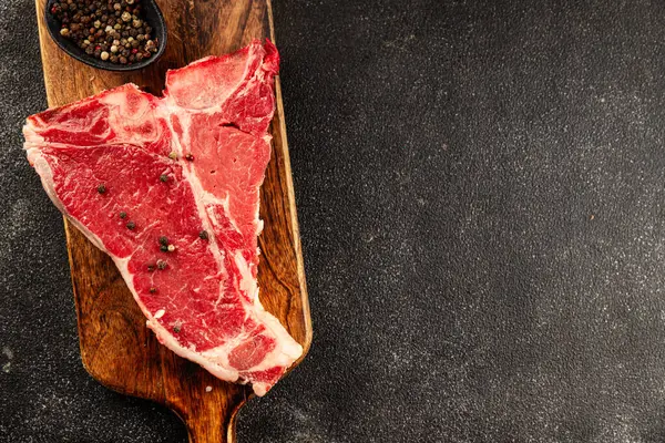 Çiğ biftek T-bone taze et prim biftek aperatif taze lezzetli gurme yemek arka planı masa rustik gıda üst görünüm fotokopi alanı