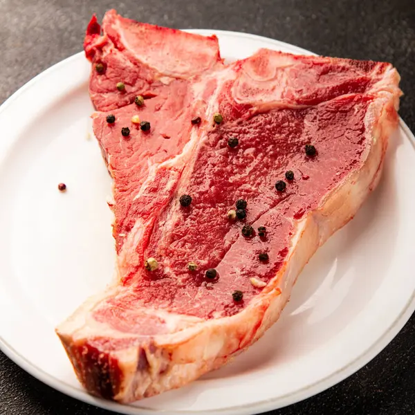 Çiğ biftek T-bone taze et prim biftek aperatif taze lezzetli gurme yemek arka planı masa rustik gıda üst görünüm fotokopi alanı